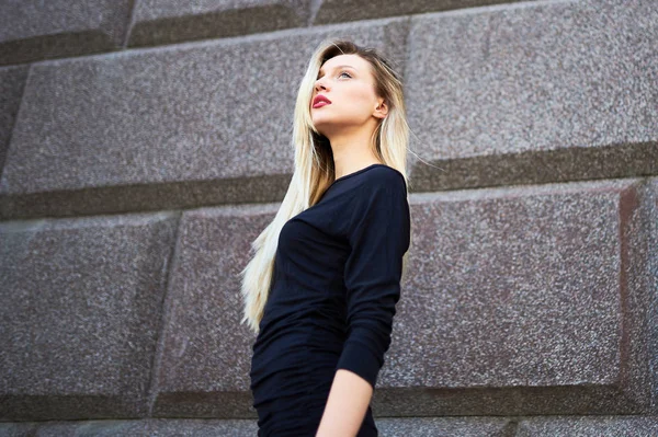 Vacker blond tjej med rött läppstift. Mot bakgrund av en stenmur. — Stockfoto