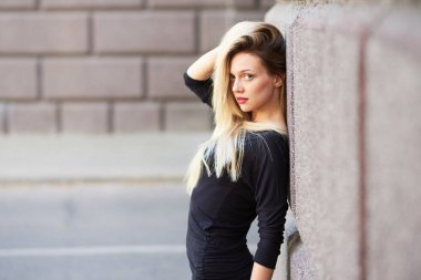 Kırmızı rujlu güzel sarışın kız. Saçları düzleştirir. Taş bir duvarın arkasında.