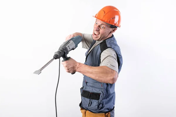 A builder with a funny expression, in a helmet, with a drill in his hands. — 스톡 사진