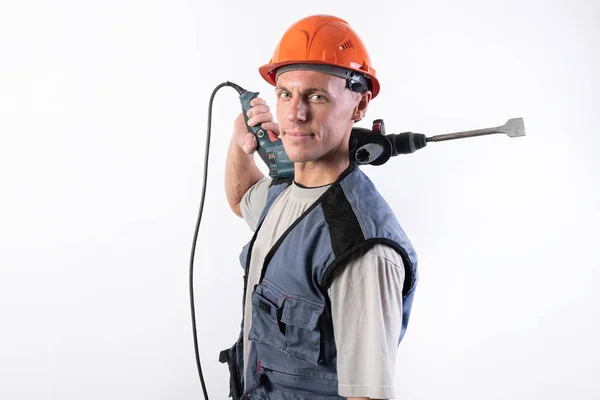 Un constructor con una expresión divertida, en un casco, con un taladro en el hombro . — Foto de Stock