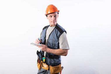 Not defteri olan bir inşaatçı. Kask ve bornozla. Veri yazar.