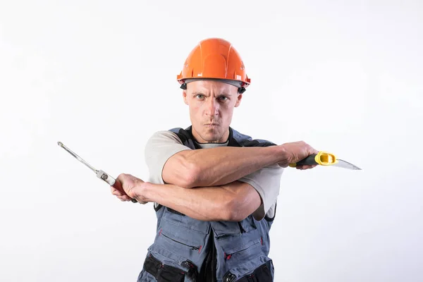 Un constructor con sierras en un casco se burla. Sobre un fondo claro . —  Fotos de Stock