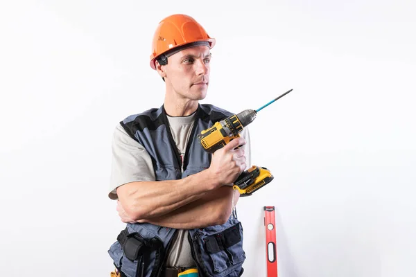 Construtor reparador segurando uma broca como uma arma. Em um capacete e roupa de trabalho . — Fotografia de Stock