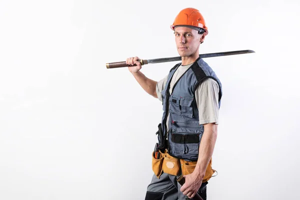 Un constructor con una gran espada en el hombro. Reparador con casco y ropa de trabajo . — Foto de Stock