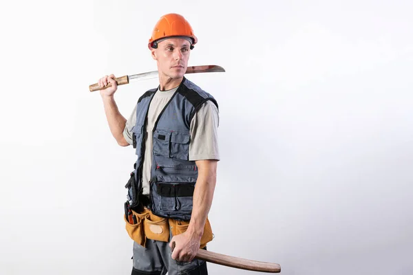 Un constructor con una katana corta en una mano y una funda en la otra. Reparador con casco y ropa de trabajo . —  Fotos de Stock