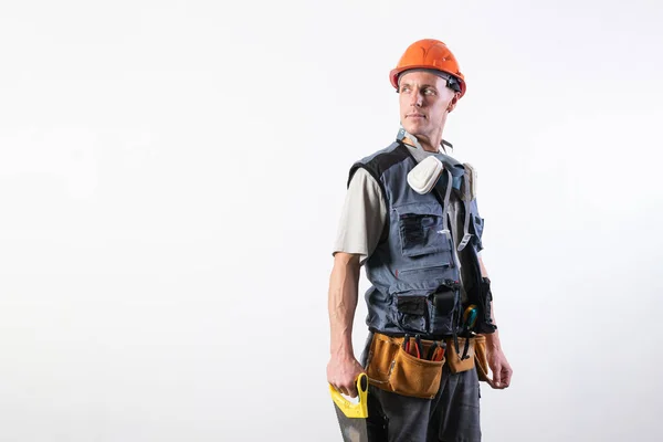 Constructor con sierra. Con ropa de trabajo y casco. Sobre un fondo gris claro . —  Fotos de Stock
