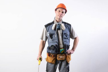 Testereli bir inşaatçı. İş kıyafetleri ve kaskla. Açık gri bir arkaplanda.