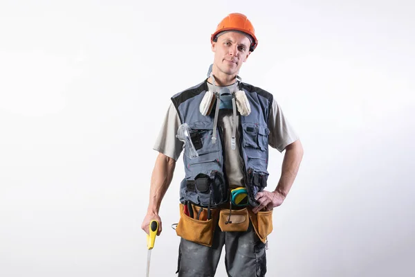 Constructor con sierra. Con ropa de trabajo y casco. Sobre un fondo gris claro . — Foto de Stock