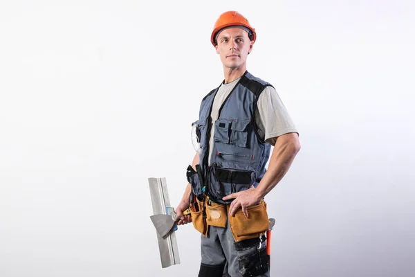 Constructor orgulloso con una paleta. Con ropa de trabajo y sombrero duro. Sobre un fondo gris claro . — Foto de Stock
