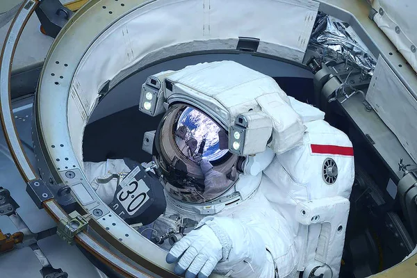 En astronaut i en rymddräkt klättrar ut ur luckan. Delar av denna bild tillhandahölls av Nasa. — Stockfoto