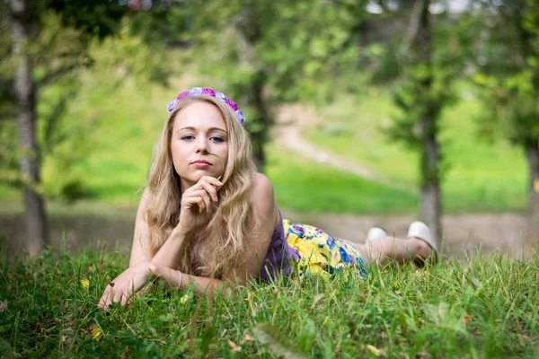 Çimlerin üzerinde sarışın bir kız. Düşünceli bir ifadeyle. — Stok fotoğraf
