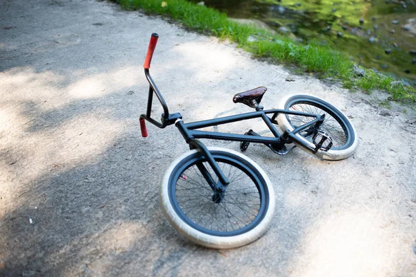 Велосипед BMX лежит на тротуаре в парке . — стоковое фото