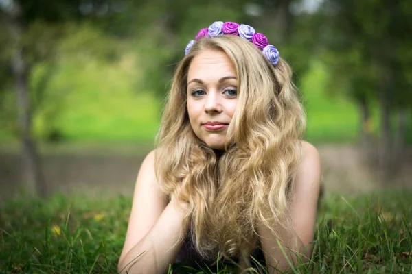 Schöne blonde Mädchen liegt im Gras und sieht in den Rahmen. — Stockfoto