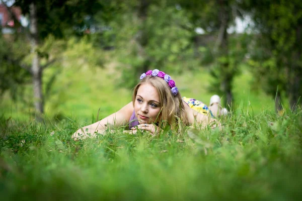 Schöne blonde Mädchen. auf dem Gras liegend und nachdenklich zur Seite blickend. — Stockfoto