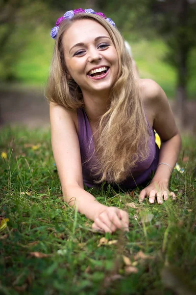 Schöne blonde Mädchen liegt im Gras und lacht. — Stockfoto