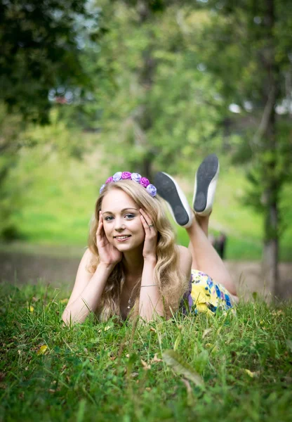 Vacker blond flicka som ligger i gräset och ler. — Stockfoto