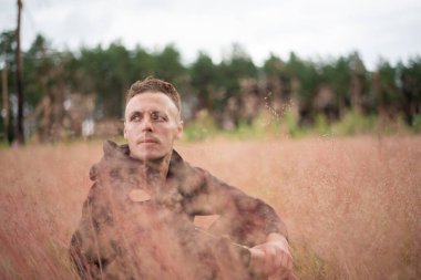 Adam kalın bir tarlada oturuyor ve düşünüyor..