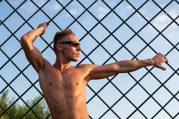 Un uomo atletico posa dietro le sbarre di ferro . — Foto Stock
