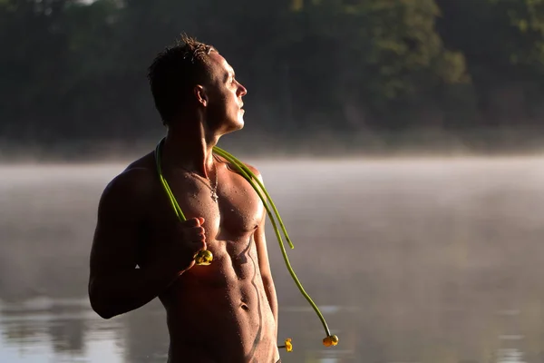Un bellissimo uomo in acqua, con una torta nuda. Al tramonto . — Foto Stock