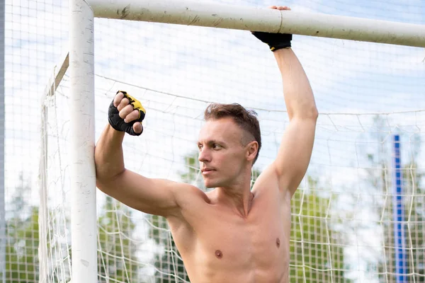 Uomo muscolare sul campo di calcio, vicino al palo della porta . — Foto Stock