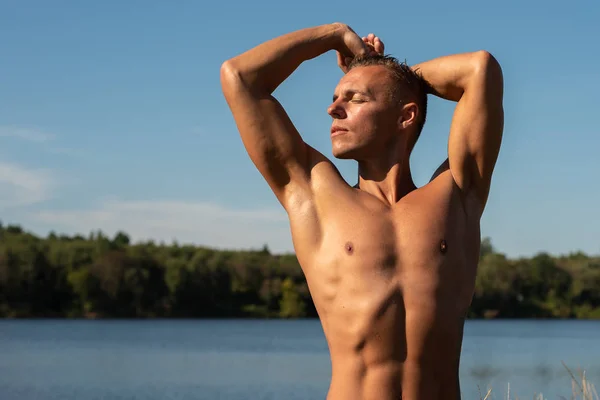 Un bellissimo uomo muscoloso su un lago in acqua . — Foto Stock
