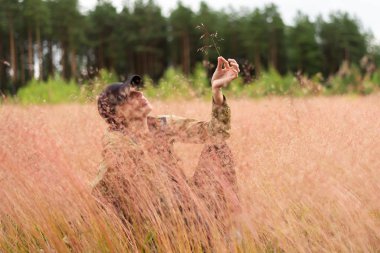 Çimenlerde, tarlada oturan yetişkin bir kadın. Herhangi bir amaç için.