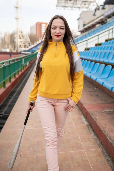 Girl with a bat in an empty stadium. For any purpose