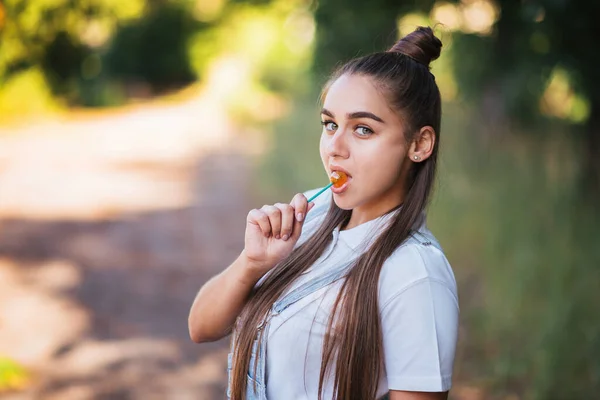 Girl with a candy on a stick on the nature. For any purpose.