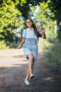 Kot pantolonlu bir kız gülümseyip dışarı koşuyor. Herhangi bir amaç için.