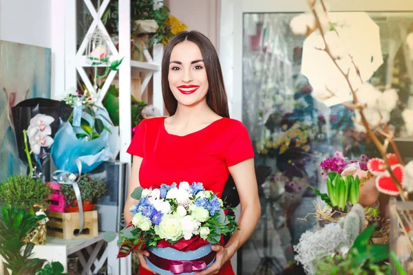 Hermosa morena en vestido rojo compra un ramo de flores en una florería — Foto de Stock