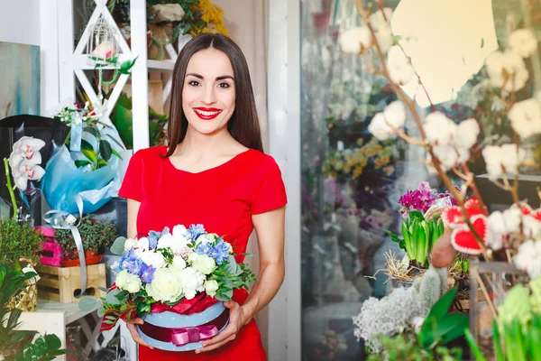 穿红色连衣裙的美丽黑发买一束鲜花在一家花店 — 图库照片