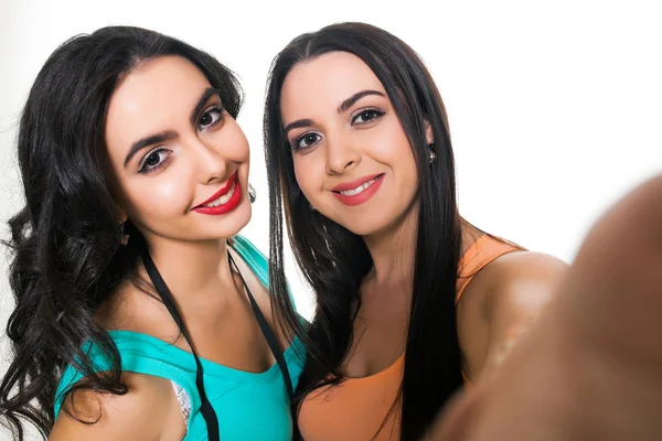 Duas meninas bonitas em um fundo branco fazendo selfie — Fotografia de Stock