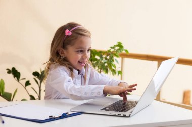 Güzel küçük bir kız ile laptop masada oturuyor