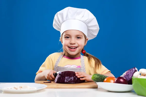 Das kleine Mädchen bereitet Salat auf blauem Hintergrund zu — Stockfoto