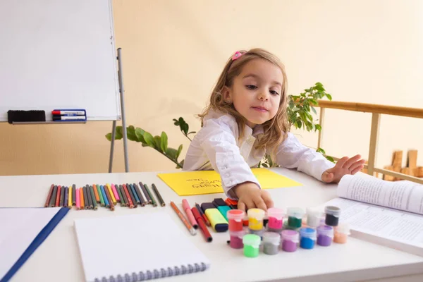 Hermosa niña dibuja sentado en la mesa —  Fotos de Stock