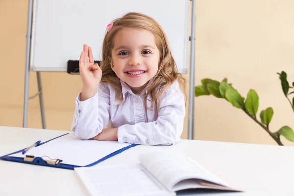 Hermosa niña escribe sentado en la mesa —  Fotos de Stock