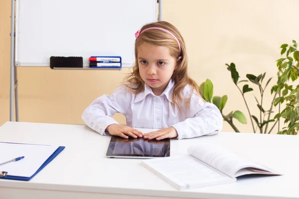 Mooi meisje zit aan tafel met tablet — Stockfoto