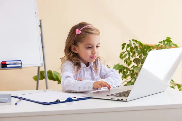 Hermosa niña está sentada en la mesa con el ordenador portátil —  Fotos de Stock