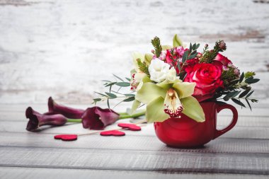 Small red vase with bouquet of flowers and Lilies on wooden table space for text clipart