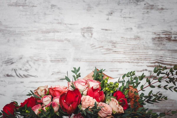 Veel rozen en bloemen liggen op de achtergrond van een houten muur — Stockfoto