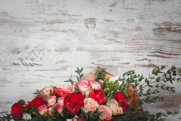 Mnoho růže a květiny leží na pozadí dřevěné stěny — Stock fotografie