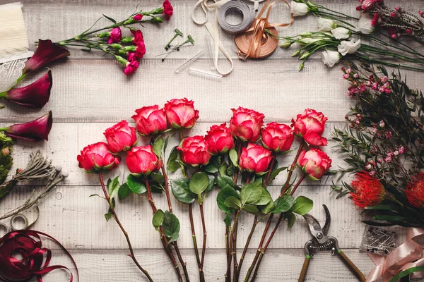 Anjers, rode rozen, roze callas op een houten tafel in een bloemenwinkel — Stockfoto