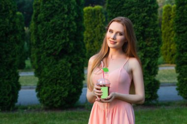 Bahçede suyu içme pembe elbiseli güzel genç kız