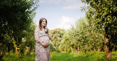 Hamile kadın tek başına bir çayır yürür ve içecekler suyu