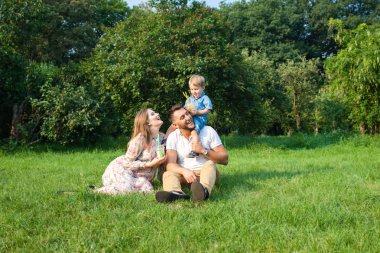 Genç çekici aile ile çocuk bir çayırda oynarken ve suyu içme