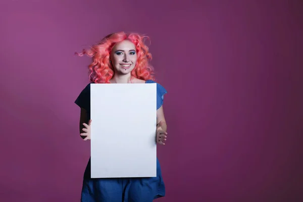Девушка с розовыми волосами с белым полотном на сиреневом фоне, место для текста — стоковое фото