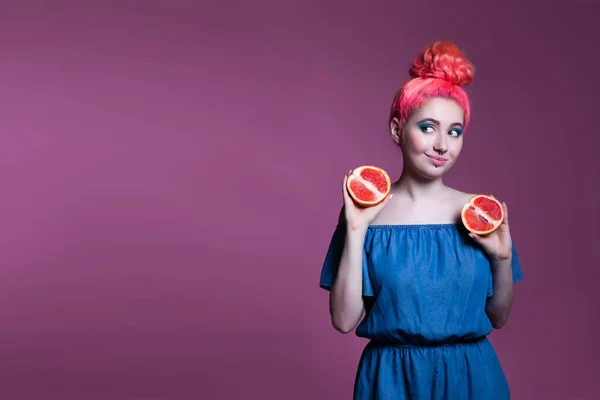 Niña con pelo rosa con mitades de pomelo sobre fondo lila, lugar para el texto — Foto de Stock