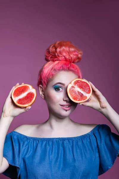 Niña con pelo rosa con mitades de pomelo sobre fondo lila, lugar para el texto — Foto de Stock