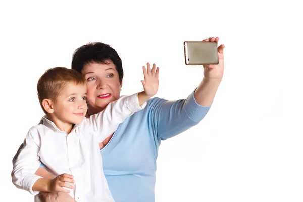 Großmutter umarmt ihren Enkel auf weißem Hintergrund und macht Selfie — Stockfoto