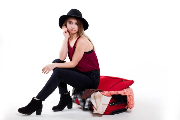 Jente som prøver å lukke den store kofferten full av ting på hvit bakgrunn – stockfoto
